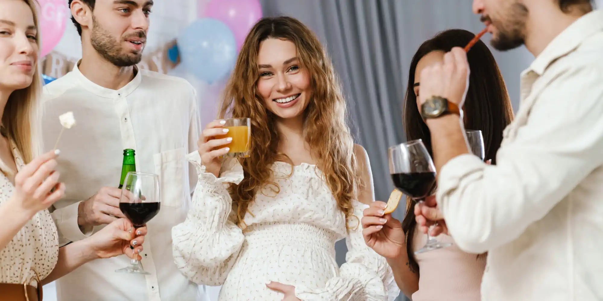A group of smiling adults at a party with drinks and snacks.