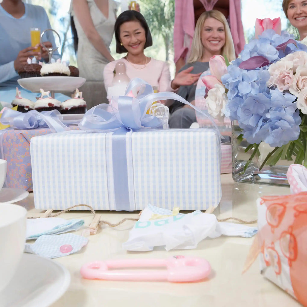 A baby shower gift wrapped in blue and white striped paper with a blue bow.