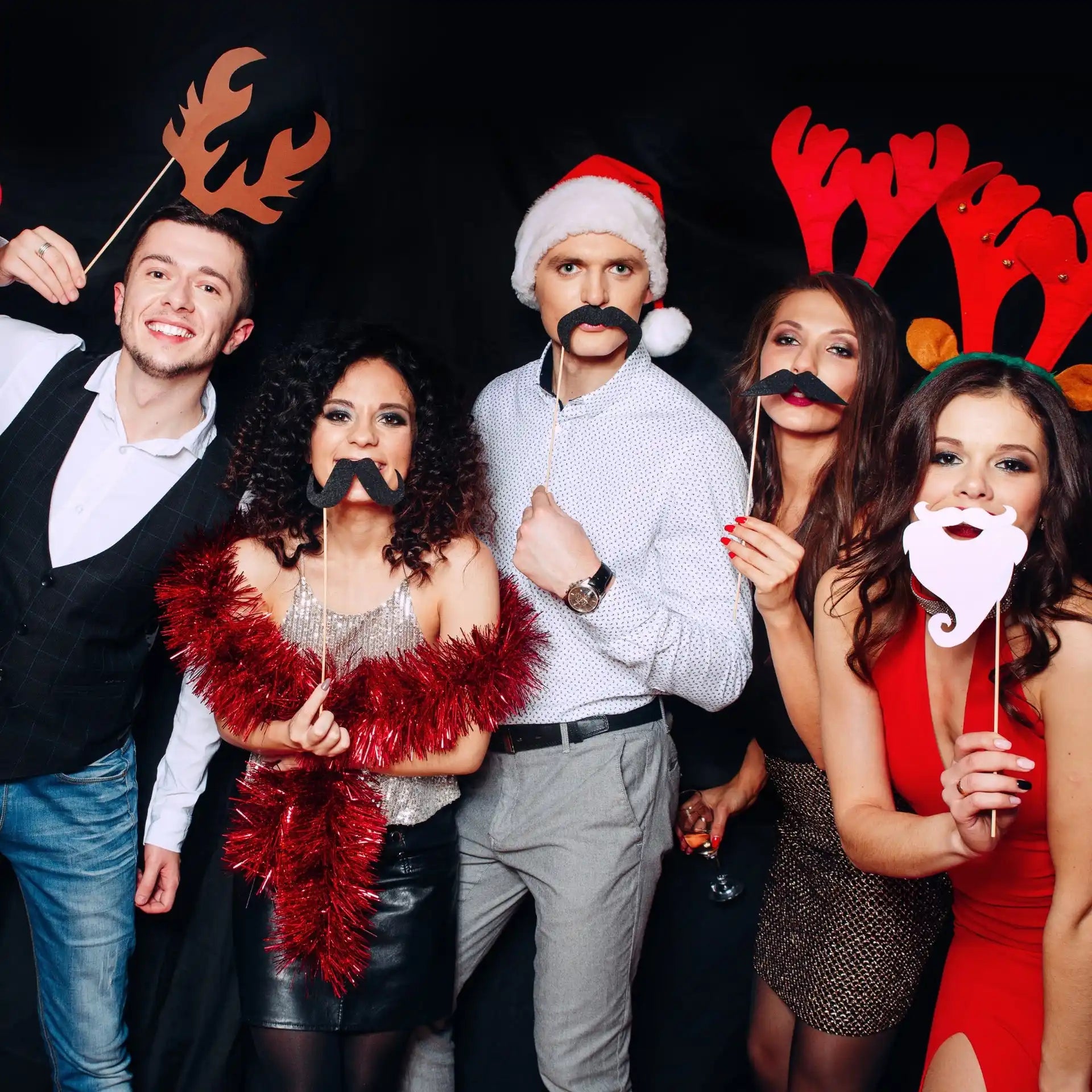 Five adults posing with photo booth props.