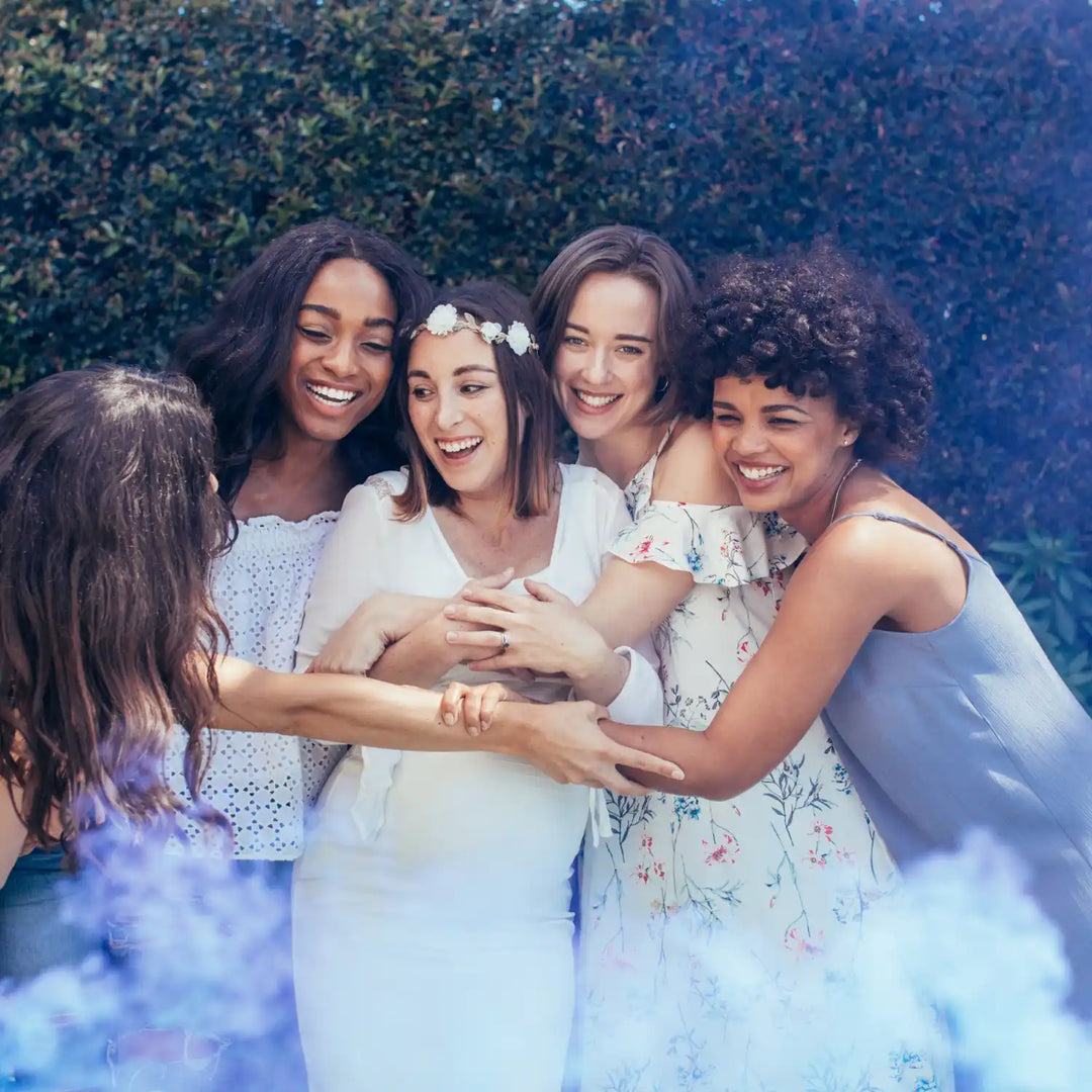 A group of friends in white dresses hugging and laughing together