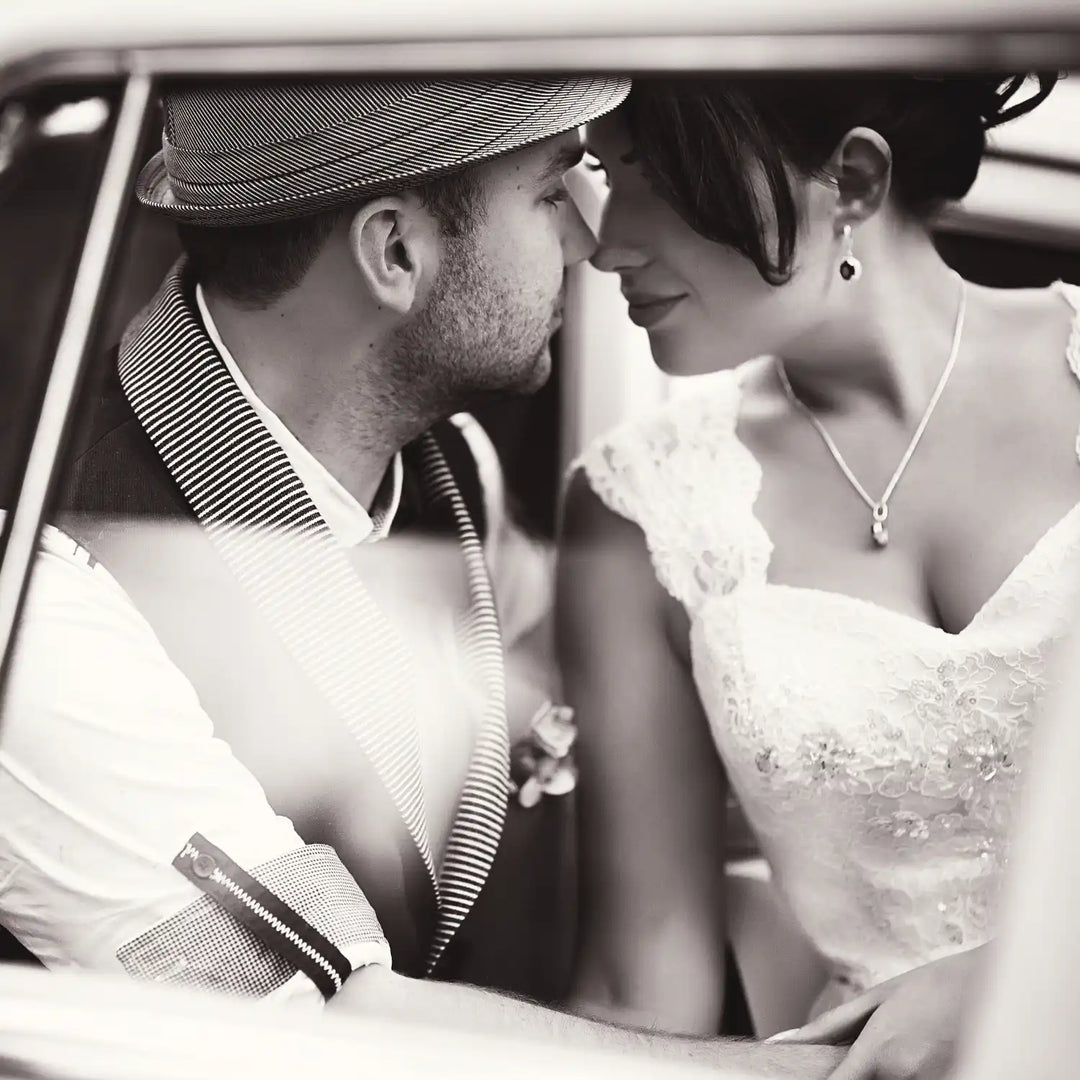 A romantic black and white wedding photograph captured inside a car