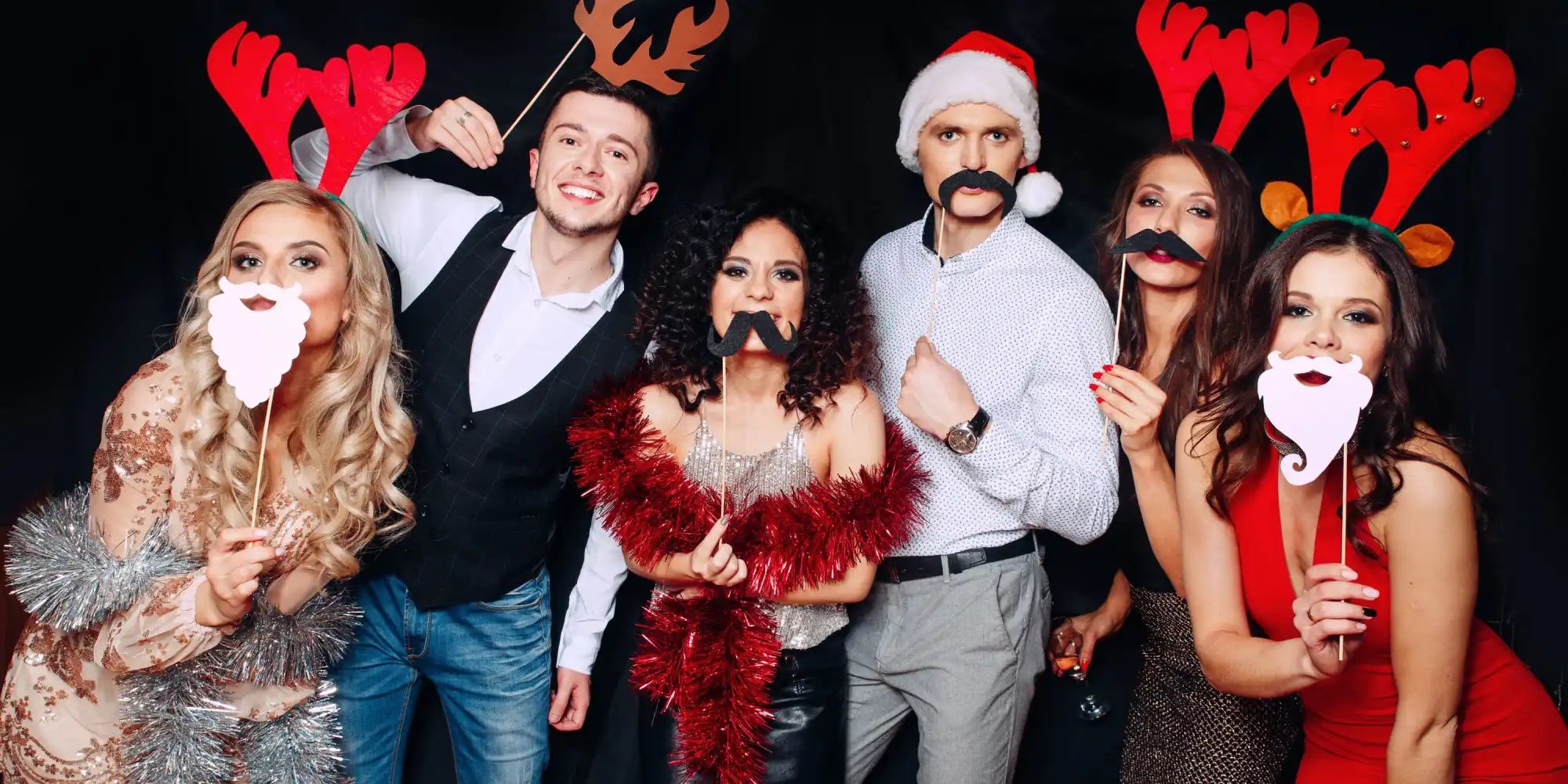 Six adults celebrating Christmas with festive props.